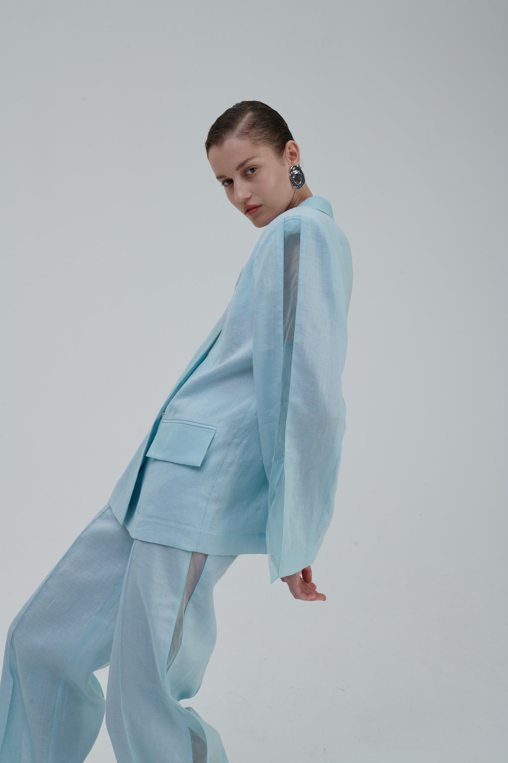Light blue women’s designer blazer on model with sheer sleeve detail