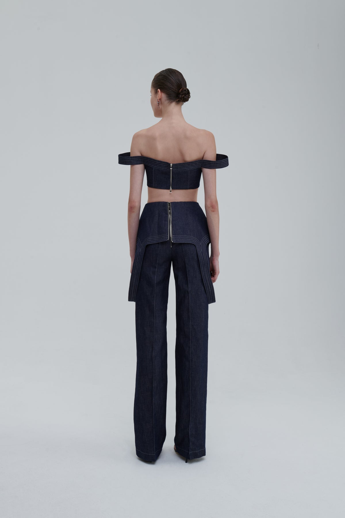 Dark blue designer denim trousers back view on model with matching top